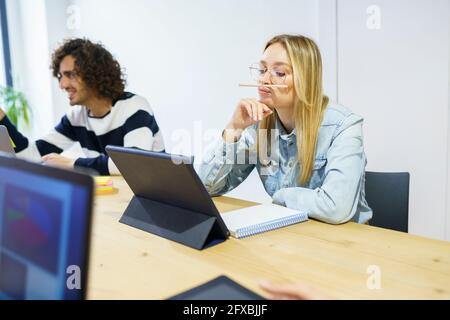 Thoughtful blond businesswoman with hand on chin working in office Stock Photo