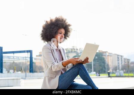 Female entrepreneur using laptop while sitting outdoors Stock Photo