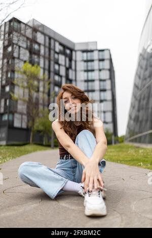 Woman sitting on footpath Stock Photo
