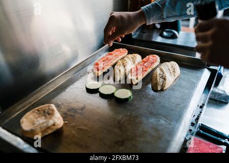 Waiter seasoning veggies while preparing sandwich in a restaurant Stock Photo