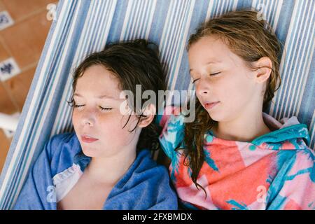 Brother and sister in bathrobe sleeping in hammock Stock Photo