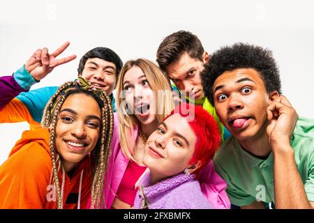 Young friends enjoying while making faces on white background Stock Photo