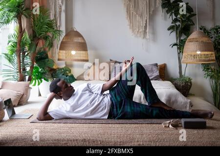 African yoga man doing anantasana pose working out at home Stock Photo