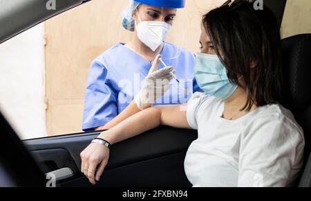 Woman getting COVID-19 vaccine in car at drive through Stock Photo