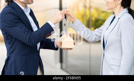 Male real estate developer with architectural model giving house key to businesswoman Stock Photo