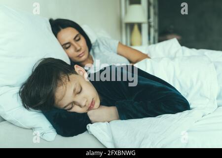 Son sleeping with his mother on bed. Mother and son sleeping together