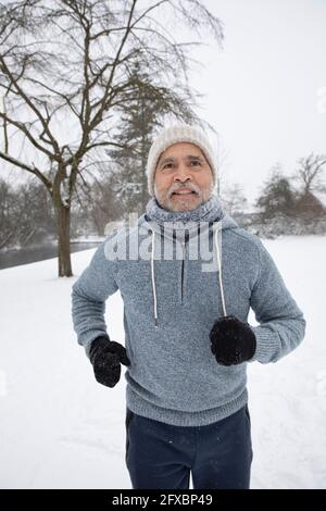 Man wearing knit hat and hooded shirt running at park Stock Photo