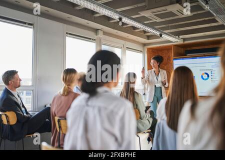 Businesswoman explaining business plan to colleagues in educational event Stock Photo