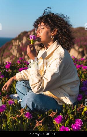Young woman with curly hair smelling carpobrotus edulis Stock Photo