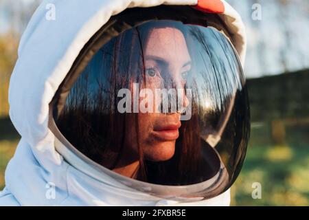 Female explorer wearing space helmet looking away in forest Stock Photo