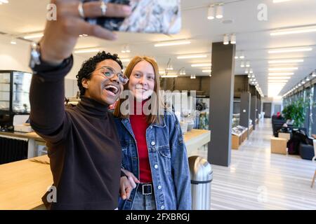 Female friends taking selfie with mobile phone in restaurant Stock Photo