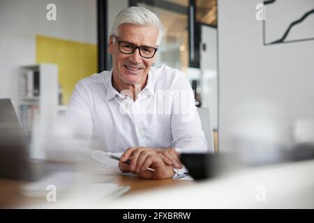 Mature entrepreneur smiling in office Stock Photo