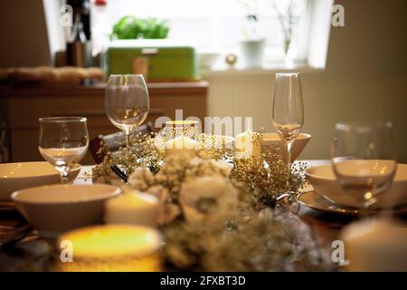 Bowl and wineglasses with flowers arranged on dining table at home Stock Photo