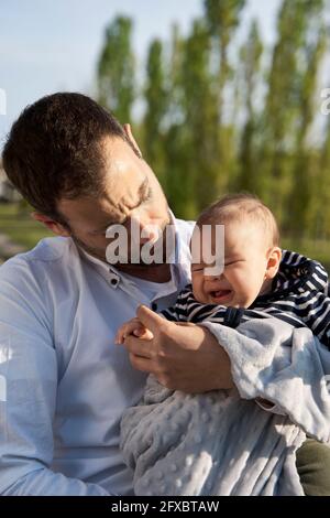 Father consoling baby boy crying at park Stock Photo