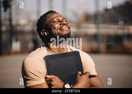 Smiling handsome man with digital tablet during sunny day Stock Photo