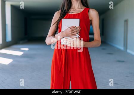 Unrecognizable woman with red dress, crossed arms and a tablet with a pen. business concept. Stock Photo