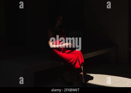 Businesswoman in shadow with a red dress holding her cell phone. Business concept. Stock Photo