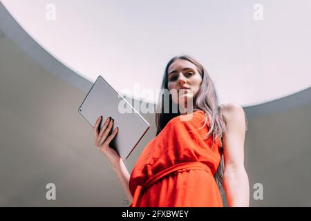 Photography from below of a business woman looking at the camera with her digital tablet in her hand. Stock Photo