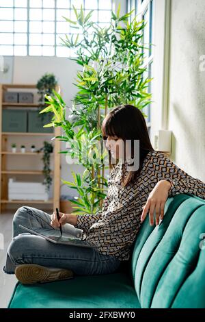 Female graphic designer using tablet while sitting on sofa at office Stock Photo