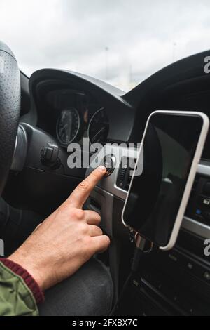 Man pushing start button in car Stock Photo