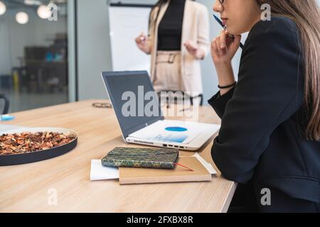 Businesswoman analyzing financial data over laptop at office Stock Photo