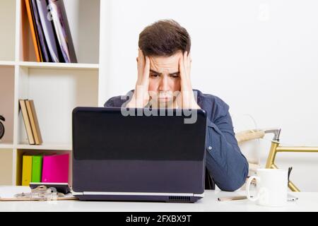 young man in front of the computer laptop concentrated or overwhelmed Stock Photo
