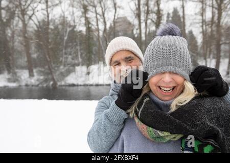 Playful man covering woman face with knit hat at park Stock Photo