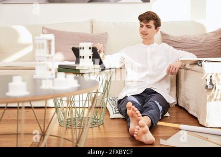 Male architect using digital table in front of sofa at home Stock Photo