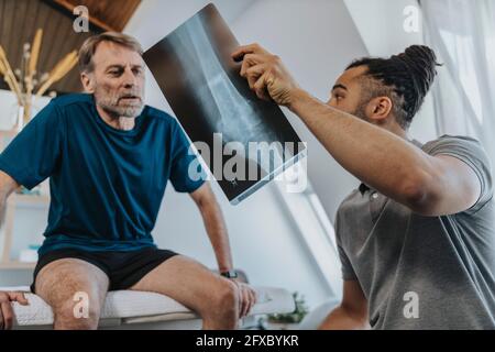 Physiotherapist discussing x-ray image of knee with male patient Stock Photo