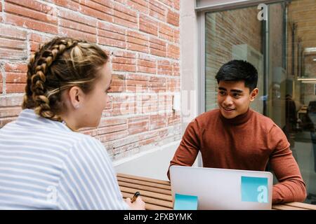 Young male and female professionals having discussion at cafeteria Stock Photo
