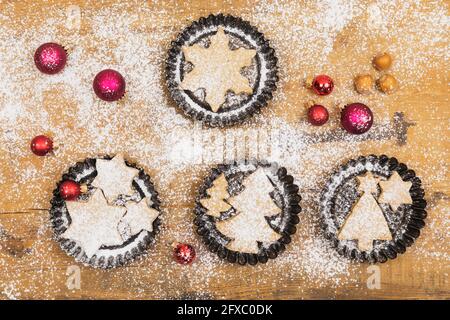 Christmas ornaments and fresh homemade cookies lying on wooden surface Stock Photo