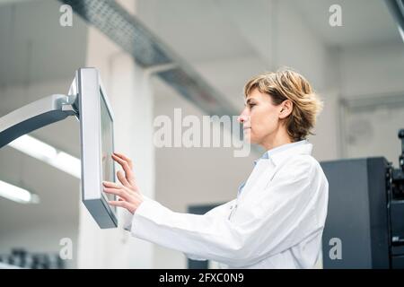 Technician wearing lab coat operating printing machine in laboratory Stock Photo