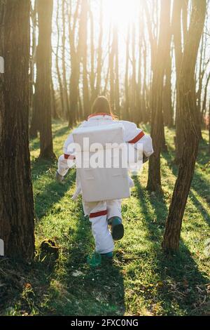 Female astronaut wearing space suit running in forest Stock Photo