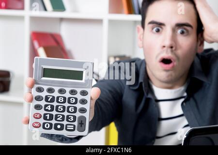 calculator in first plane with man afraid Stock Photo