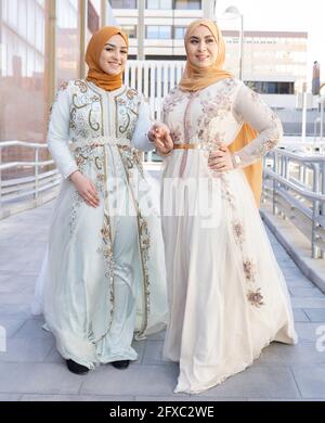 Friends in fashionable dress holding hands while standing on bridge Stock Photo