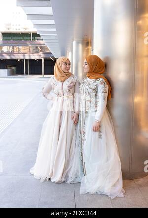 Female friends in fashionable dress standing on footpath Stock Photo