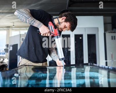 Male glazier with equipment working on glass at garage Stock Photo