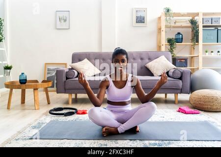 Smiling young woman practicing yoga at home Stock Photo