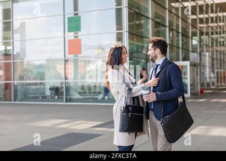 Colleagues talking while standing on footpath Stock Photo