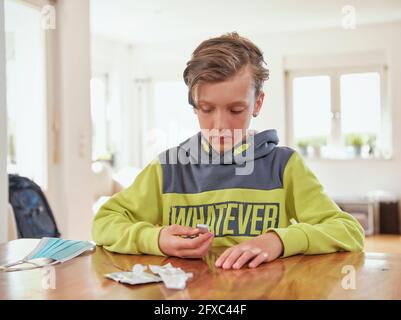 Serious boy analyzing covid-19 test at home Stock Photo