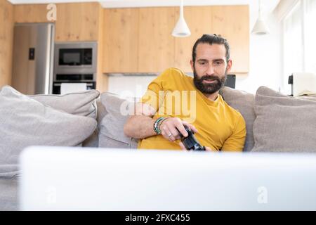 Man with joystick playing video game at home Stock Photo