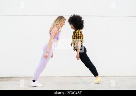 Multi-ethnic female friends standing tilt by wall Stock Photo