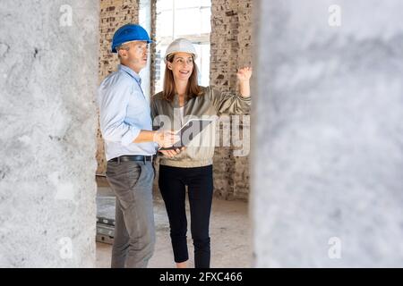 Female client gesturing while discussing with male architect at construction site Stock Photo