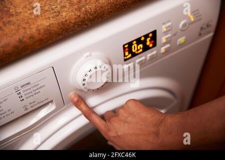 Woman operating washing machine at home Stock Photo