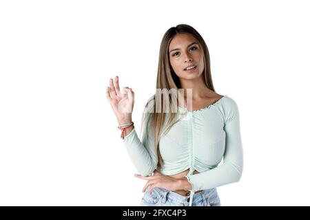 Beautiful Latin woman making the ok gesture with her hand and looking straight ahead on a pure white background. Stock Photo