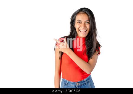 Young smiling dark haired Latin woman pointing to her right on a pure white background. Stock Photo