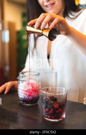 Female bartender pouring cocktail in glass at counter Stock Photo