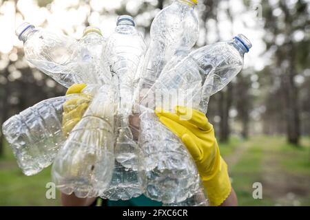 Volunteer holding crumpled plastic bottles in forest Stock Photo