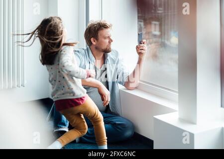 Man using mobile phone while sitting by girl at home Stock Photo