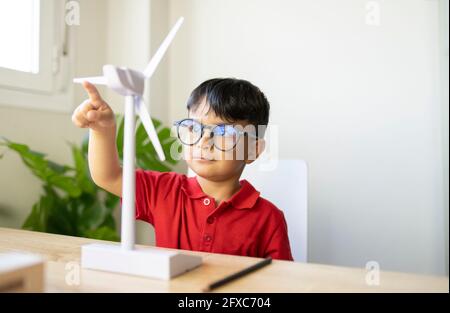 Boy wearing eyeglasses playing with wind turbine model at home Stock Photo